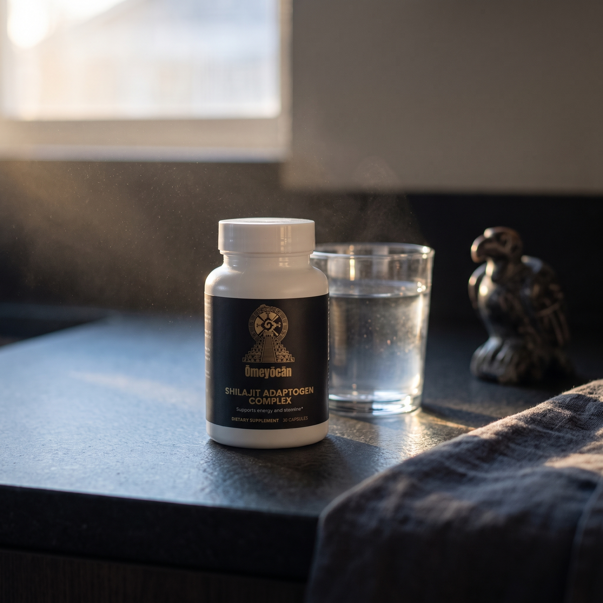 Omeyocan Shilajit Adaptogen Complex bottle on a dark stone counter at dawn, morning ritual scene