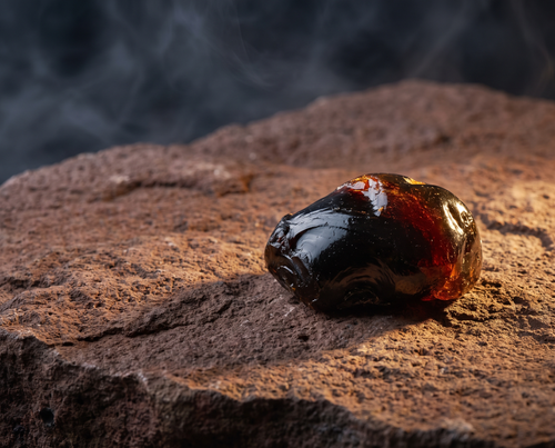 Shilajit resin on reddish-brown Andean volcanic stone ledge